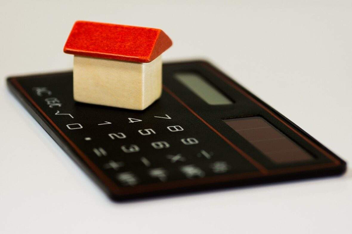 Toy house on top of calculator depicting number crunching for home purchase
